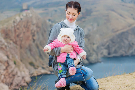 年轻的母亲和婴儿在海边的山里散步