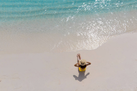女孩独自在海边, 享受阳光。头草帽和黄色泳衣的年轻女子