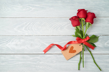 s day concept with rose flowers and gift tag on wooden backgroun