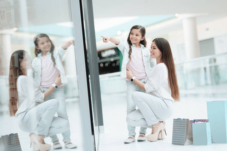 女儿正坐在商场里妈妈的腿上。妈妈和女孩在微笑