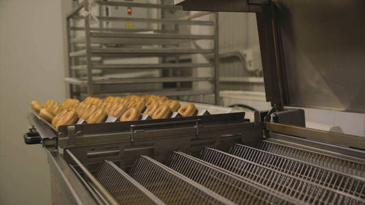 甜甜圈的工业生产。现场。面包店面包业糖果厂饼干百吉饼或甜甜圈在面包店的甜品工厂做了很多事情