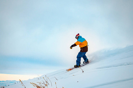 那家伙正骑着滑雪板。在原始的雪地里的山里。吉尔吉斯斯坦山脉