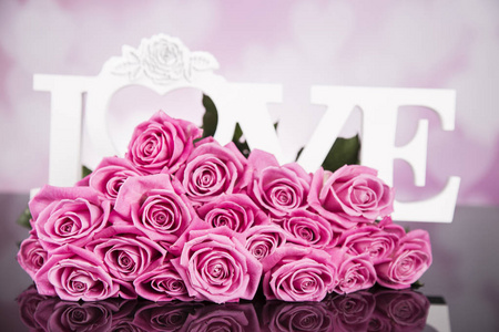 黑色背景上的一束粉红色玫瑰，上面写着爱。