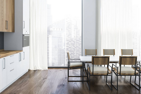 厨房内部有白色墙壁，木制地板，大窗户，白色台面，木制橱柜和长白色桌子和椅子。3D渲染