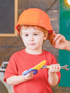 教育游戏的概念。玩玩具工具的孩子。男性手捧橙色防护头盔