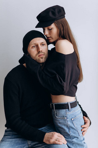 两个时髦的模特一男一女穿着空白的黑色t恤，牛仔裤和摆姿势。戴着黑色帽子，帽子，爱，亲吻