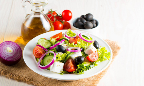 新鲜的希腊沙拉，由樱桃番茄鲁科拉阿古拉法塔橄榄黄瓜洋葱和香料制成。 凯撒沙拉在一个白色的碗在木制的背景。 健康有机