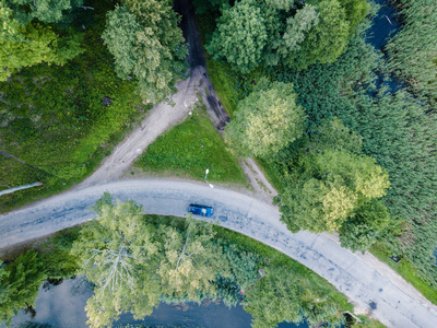 空中摄影汽车在河边行驶的道路上，在树下自上而下地观看乡村和谐自由的和平生活理念