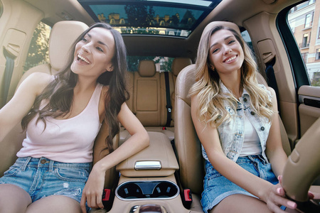 两个微笑的年轻女人坐在豪华车上