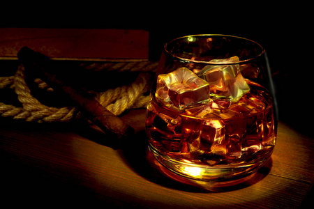 威士忌, 干邑或白兰地与冰在玻璃和吸烟管在质朴的木材背景, 复制空间