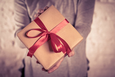 特写可爱的礼品盒礼物，用红色丝带和再生纸包裹在爱情惊喜生日庆祝圣瓦伦丁日和母亲节的概念。