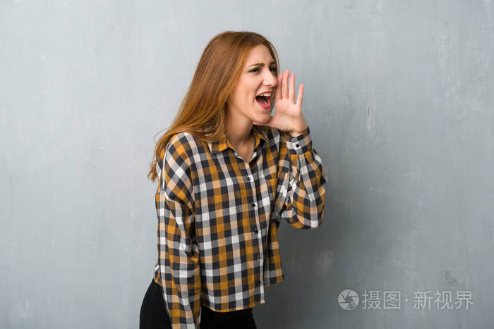 年轻的红发女孩在格朗格墙上大声喊叫,嘴巴向外侧张开