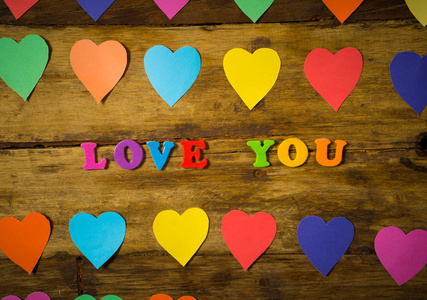 五颜六色的心和爱你的信息，用多色字母写在木制复古背景上，在圣瓦伦廷斯日主题装饰，问候卡设计和爱庆祝的概念。