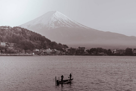 渔民在富士山前的川口湖的一艘小船上捕鱼