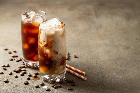 冰咖啡放在一个高杯子里，上面倒着奶油和咖啡豆。寒冷的夏天喝在棕色生锈的背景与复制空间。