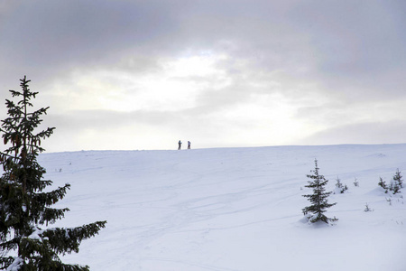 两个人站在雪山上。 人们站在山的地平线上。