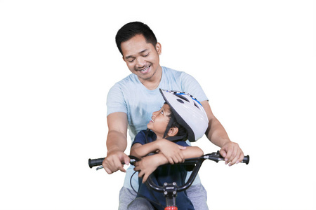 年轻人和他的儿子一起骑自行车，在画室里被隔离在白色背景上