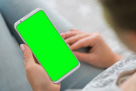 特写。模拟图像。妇女的手拿着手机绿色屏幕智能手机。色度键
