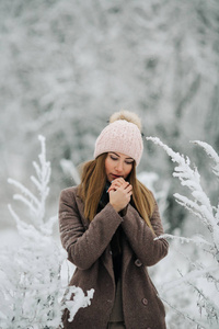 头戴帽子的金发碧眼的女人在冬天的森林里看着镜头的肖像