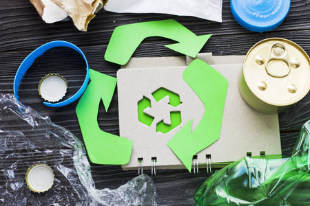 环保生态与循环利用概念回收标志记事本与垃圾在深色木制背景上特写