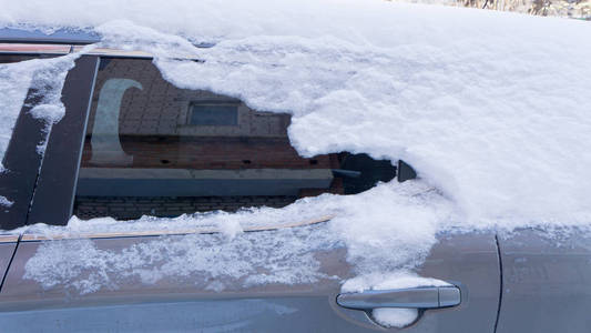 汽车上覆盖着厚厚的一层雪。 大雪的负面后果。 汽车的左边被雪覆盖