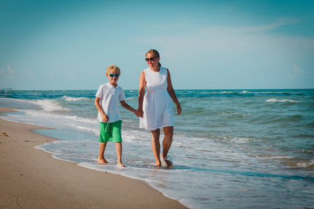 快乐的母亲和儿子走在热带海滩上