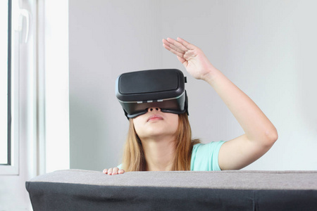 在家戴虚拟现实眼镜的年轻女人。 虚拟现实耳机是一种头部安装设备，为佩戴者提供虚拟现实。