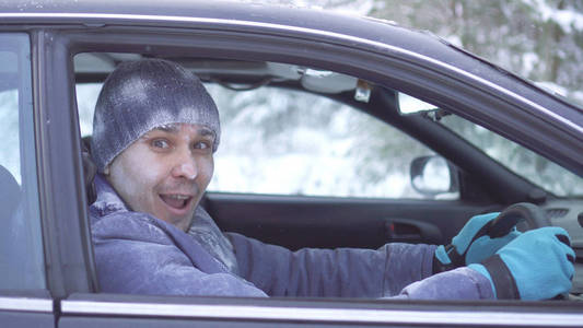 快乐的冷冻男子坐在车里看着镜头