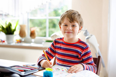 快乐微笑的小男孩在学校开学前的早晨在家做作业。小孩子在室内做运动。小学和教育 男孩画几何图形