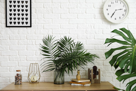 桌子旁有绿色热带叶子的花瓶，靠近轻质墙壁