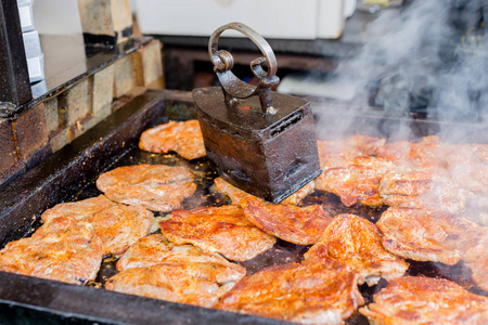 在街头美食节上, 在老式铁烤制机下, 在烧烤上烤多汁的肉牛排