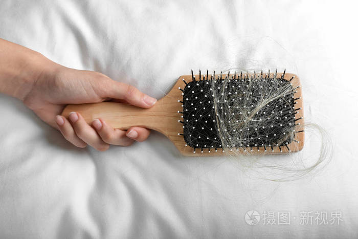 女性手拿刷子,软枕头上有掉下来的头发
