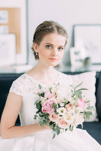 新娘在白色的工作室里拿着一束花。 欧洲风格的婚礼艺术。