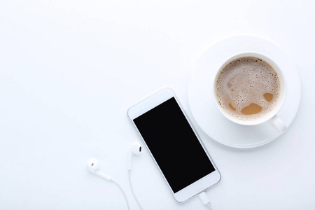 带耳机的智能手机和白色背景咖啡杯