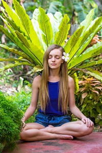 有热带植物的年轻女子在花园里冥想