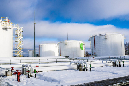 大型白色铁金属工业储罐, 用于在冬季在炼油厂存放燃料汽油和柴油以及带有阀门和法兰的管道