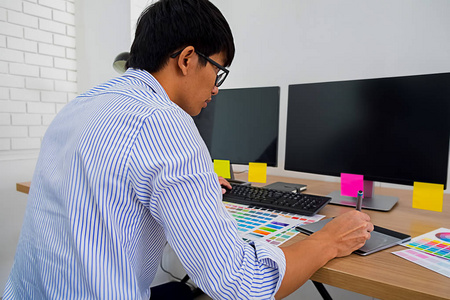 带有彩色片和平板电脑的平面设计。平面设计师在办公室用工作工具和配件在平板电脑上画一些东西。