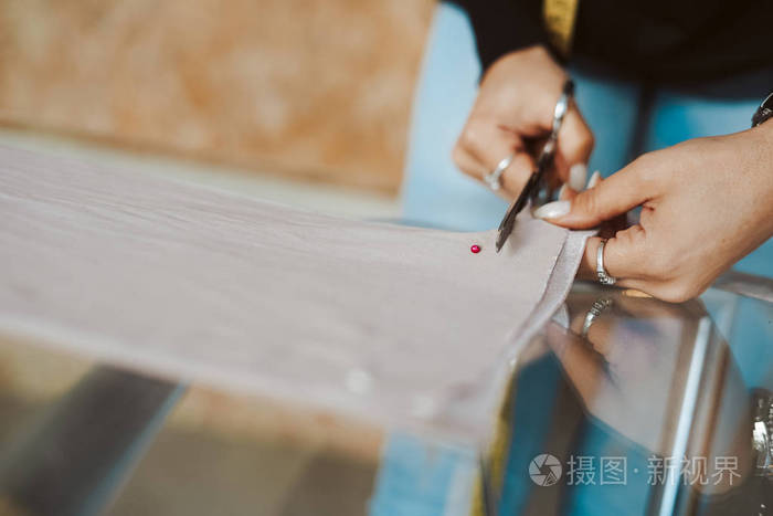 裁缝女人的手在做布料裁剪