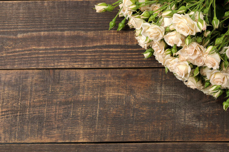 棕色木桌上美丽的迷你玫瑰框架。 美丽的花朵。 假日。 顶部视图