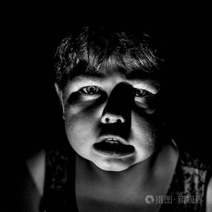 害怕的年轻白种人男孩的肖像害怕的男孩可怕和恐惧的概念黑白镜头低键