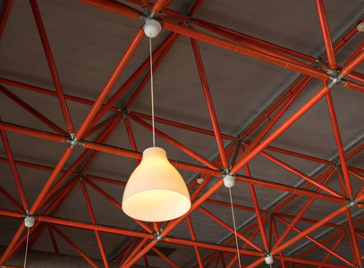 悬挂在工业红色天花板横梁上的黄灯