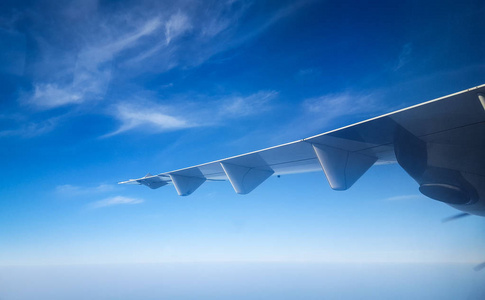 飞机的翅膀迎着美丽的蓝天云彩和海洋，从飞机的窗户飞出来