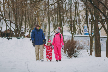 笑的家庭妇女，男人和小女孩穿着冬天温暖的衣服走在雪地公园或森林户外。节日的冬季乐趣休闲。爱童年关系家庭生活方式观念