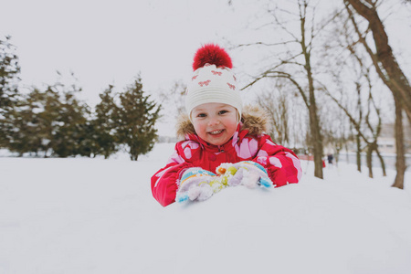 漂亮的小女孩穿着冬天温暖的衣服和帽子，在雪地公园或户外森林里玩雪球。 假日的冬季乐趣休闲。 恋爱关系家庭童年生活方式