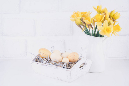 罐子里有水仙花和鸡蛋在白色的砖块背景下。 春天和复活节的概念。 水平水平