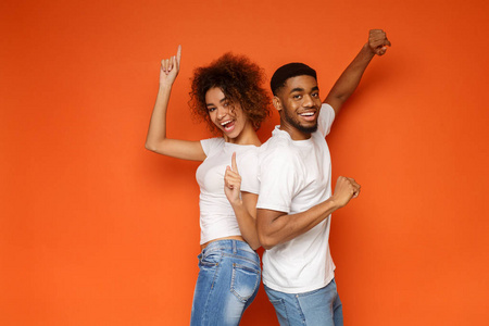 年轻可爱的非洲裔美国夫妇摆在橙色的背景