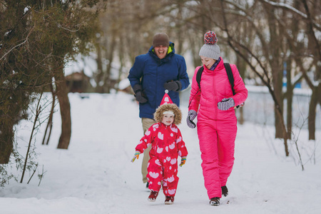 快乐的家庭女人，男人和小女孩穿着温暖的衣服，在雪地公园或森林散步。 假日的冬季乐趣休闲。 家庭生活方式观念