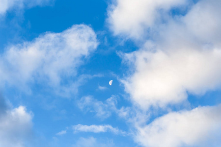 蓝天，积云和微小的半月。 自然天空背景