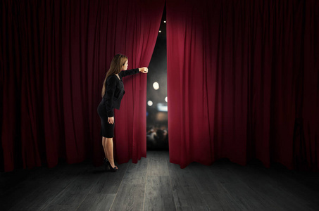 妇女打开剧院阶段的红色窗帘