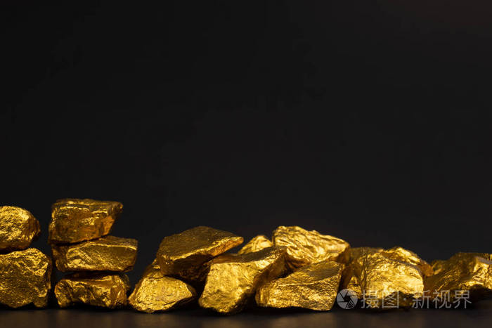 一堆金块或金矿石上的黑色背景宝石或一块金石金融和商业概念.